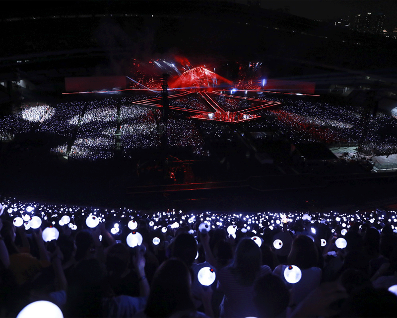 K-pop concert fans holding light sticks in the dark