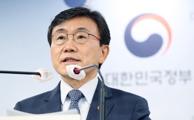 韓国の保健福祉部長官、クォン・ドクチョルがコロナ19対応に関する記者会見を行っている様子。背景には韓国政府のロゴが描かれたスクリーンが広がっている。
