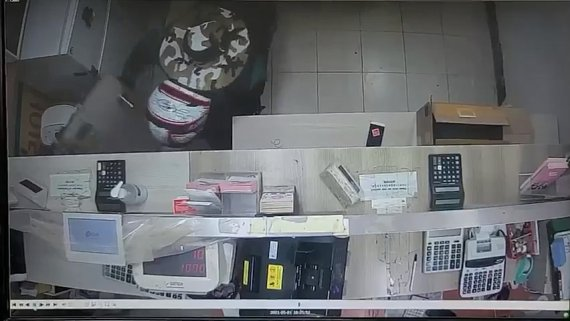 黑白監控錄影畫面，男子在換錢所內部目標著某些物品。穿戴著頭盔的男子在視頻中迅速行動，試圖避免被監控拍到。來源：南大門警察署(臺灣譯文: 黑白監控顯示一嫌疑人在換錢所內迅速行動，試圖躲避監控) 