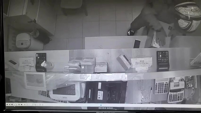 監控錄影畫面，顯示犯罪現場內疑似嫌疑人的一名男子穿戴著頭盔，雙手快速翻找換錢所辦公桌上的物品。來源：南大門警察署(臺灣譯文: 監控錄像顯示一名嫌疑人身穿頭盔在犯罪現場快速翻找桌面物品) 