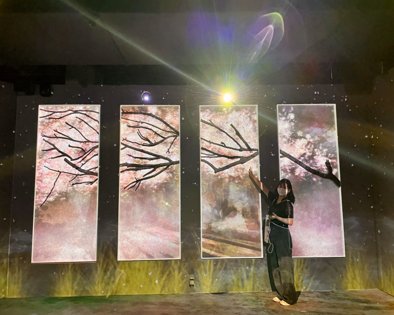 Visitatrice di fronte a una mostra digitale nella zona Rilassati di Flowers By Naked Hongdae.