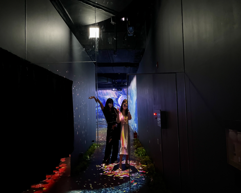 Due giovani di fronte a specchi infiniti nella zona Giardino Luminoso di Flowers By Naked Hongdae.