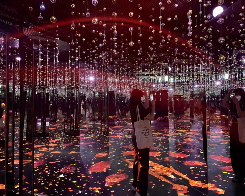 Visitatrice nel Giardino Luminoso di Flowers By Naked circondata da specchi infiniti.