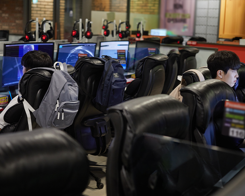 Studenti coreani con zaini in un PC bang in Corea che giocano davanti ai monitor.
