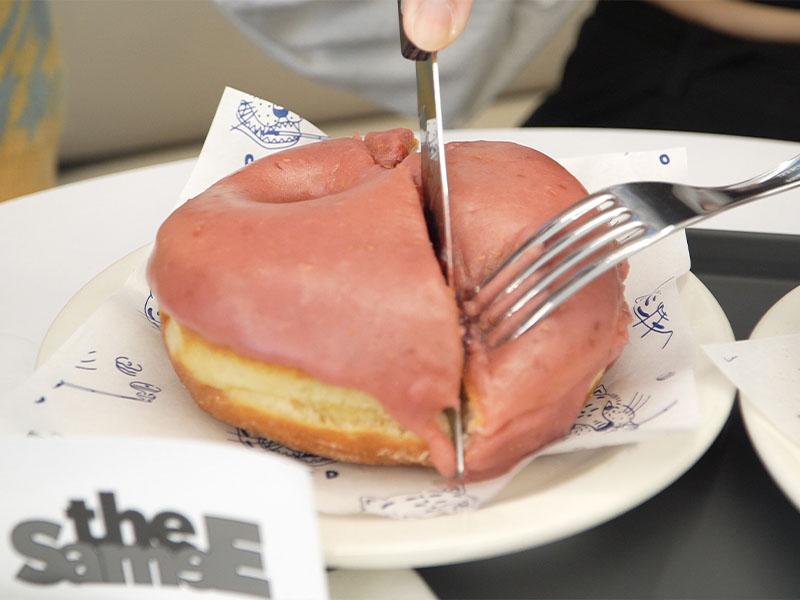 Raspberry donut being cut in half at YG the SameE cafe