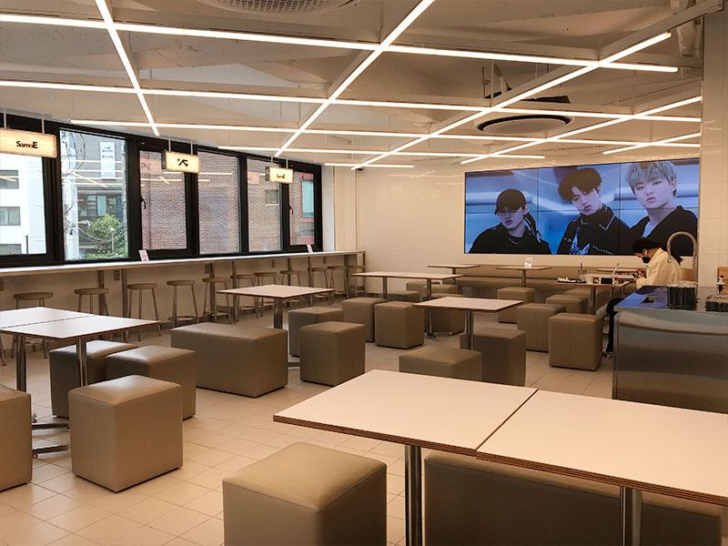 YG the SameE cafe 2nd floor seating area with a screen that plays music videos