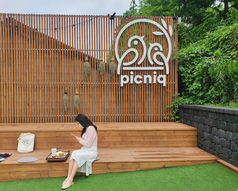 Girl sitting on a wooden deck with a wooden tray at Hongdae Picniq