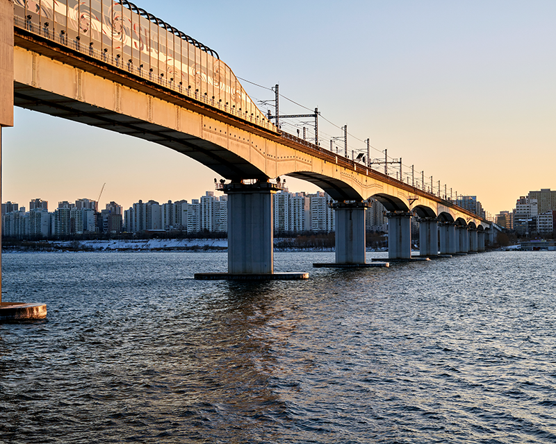 Train passing on a bridge above a river in Seoul