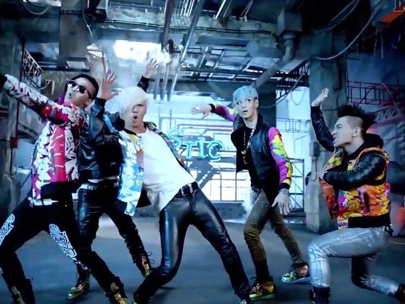 นักร้องวง Big Bang กำลังเต้นในมิวสิควิดีโอเพลง "Fantastic Baby" พร้อมฉากหลังที่เต็มไปด้วยบรรยากาศดนตรีอิเล็กทรอนิกส์