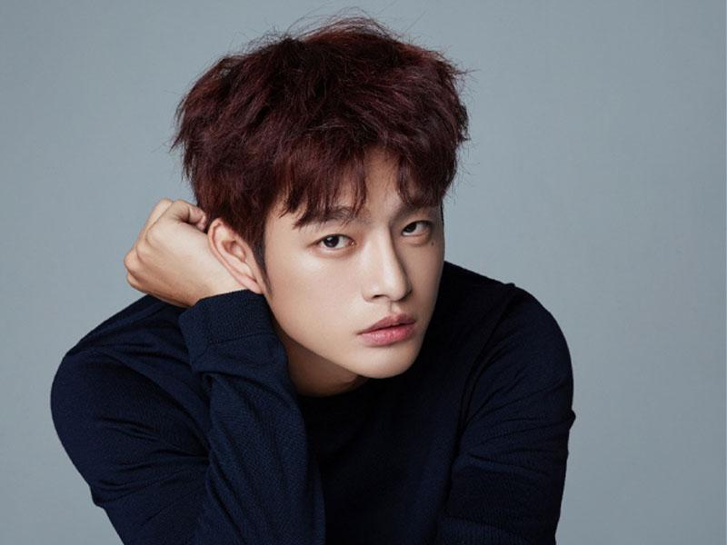 韓國男藝人徐仁國公開褐色髮色，身穿黑色上衣的肖像照片，背景為灰色