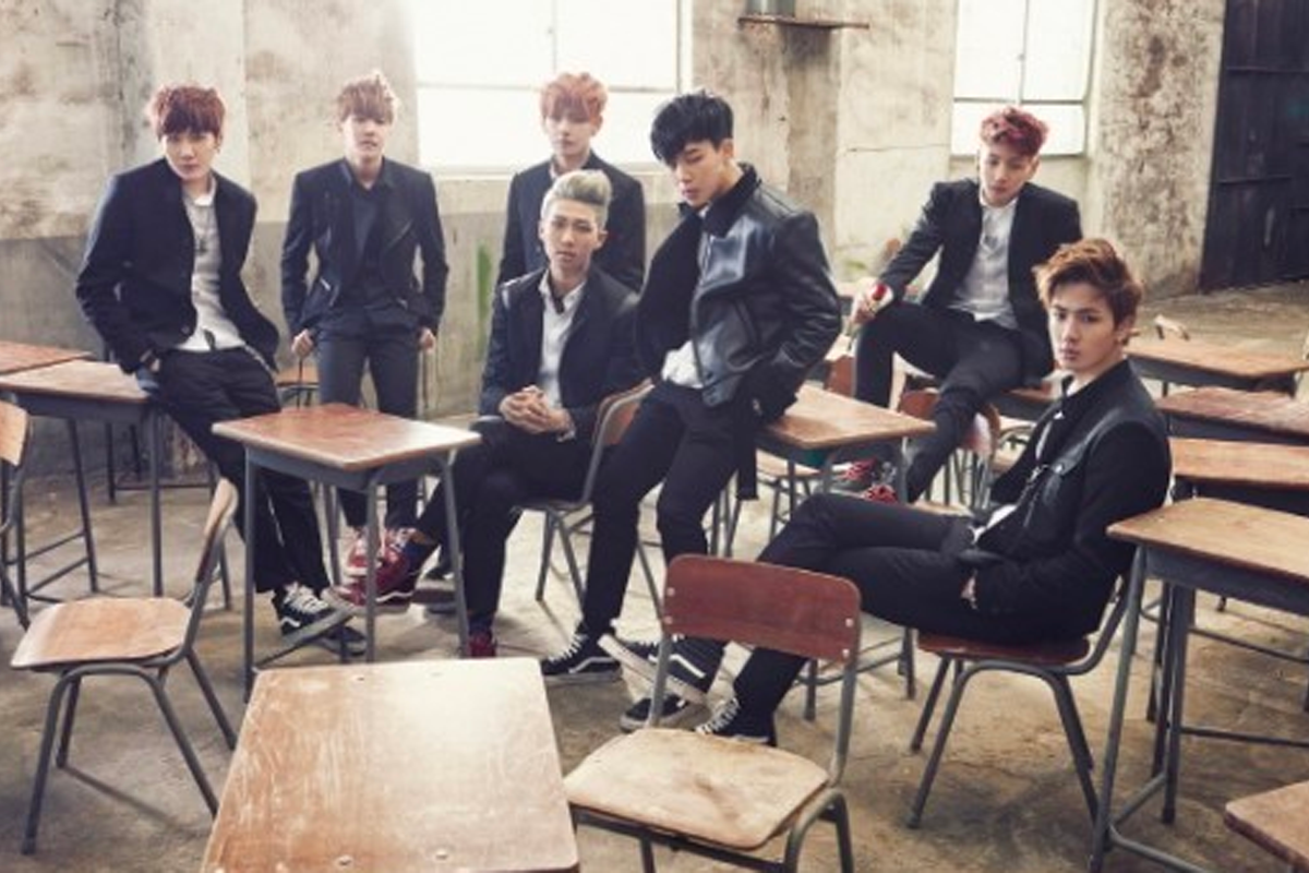 BTS dressed in school uniforms sitting in a rustic classroom setting, representing their '학교 삼부작' concept.