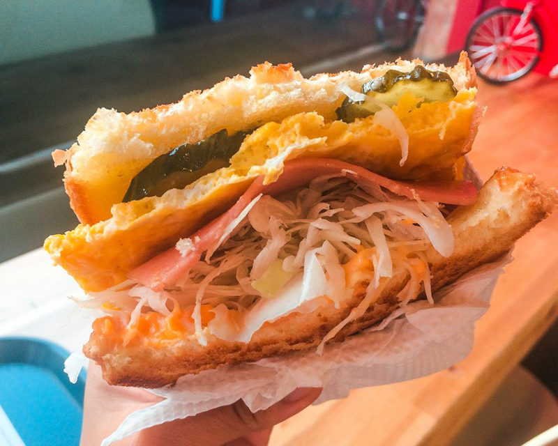 half an isaac toast sandwich with egg, pickles, ham, cheese and shredded lettuce