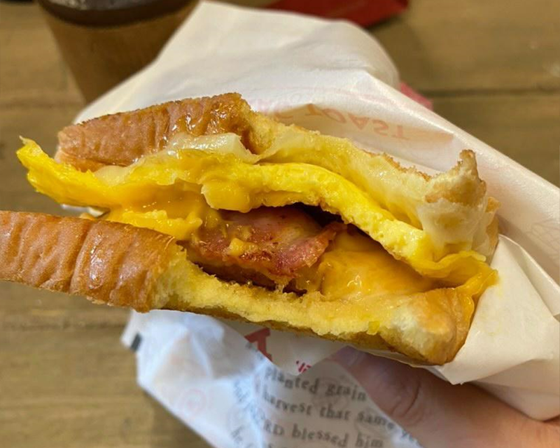 inside toast with cheese egg and bacon with a bite taken from corner from korean franchise isaac toast