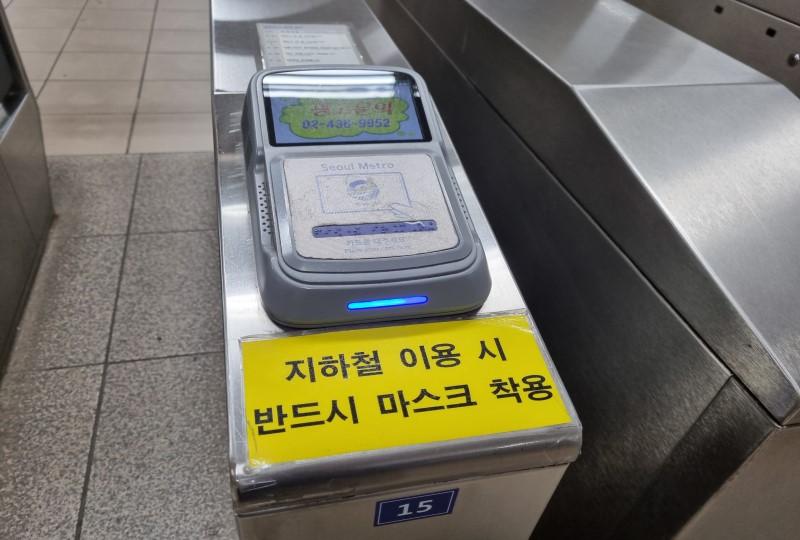 韓国の地下鉄改札にあるカード読み取り機と「マスク着用をお願いします」と書かれた黄色いステッカー。