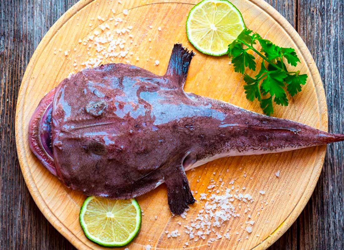 ปลาตกเบ็ดแผ่บนเขียงไม้พร้อมแต่งด้วยมะนาวและผักชี