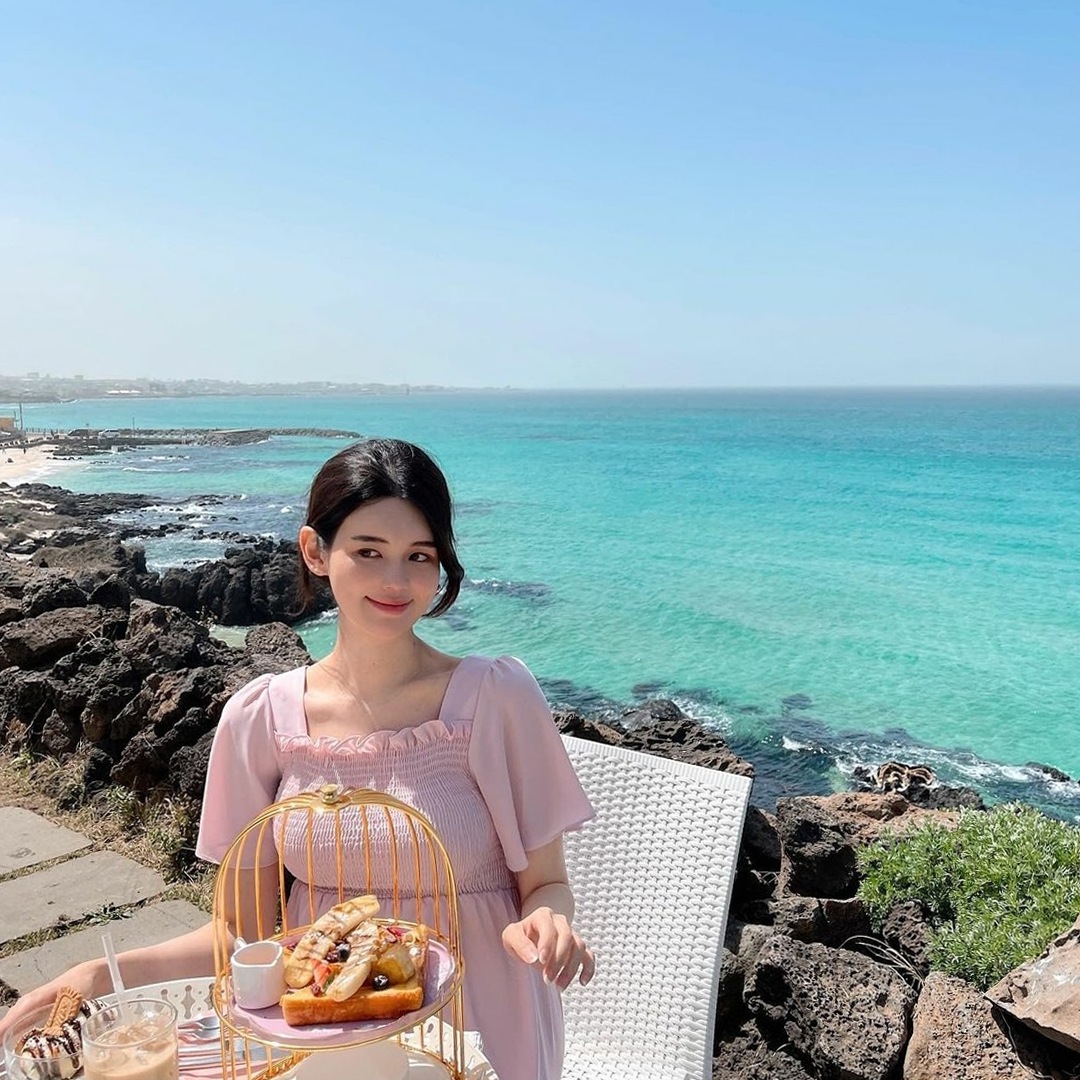 Girl wearing pink dress sitting outside Aewol The Sunset Jeju Island cafe