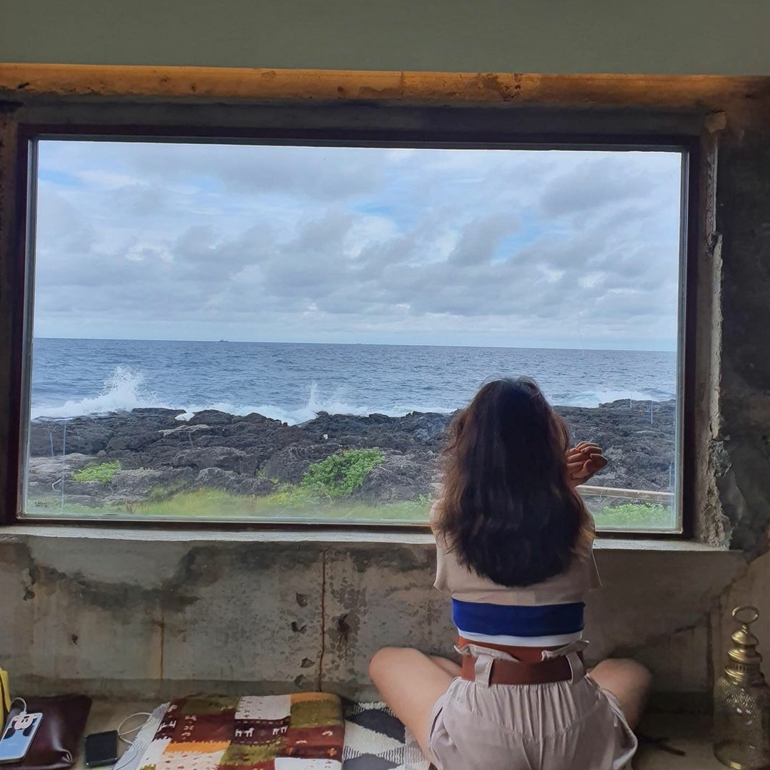 Sum & Some cafe girl sitting and enjoying the ocean view of Jeju Island 