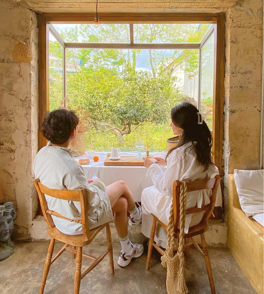 Korean couple sitting on wooden chairs near the window at Saturday Island cafe on Jeju Island 