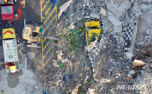 從上方拍攝的光州大樓倒塌事件畫面,顯示被倒塌建築覆蓋的黃色公共汽車和碎片散落在道路上。