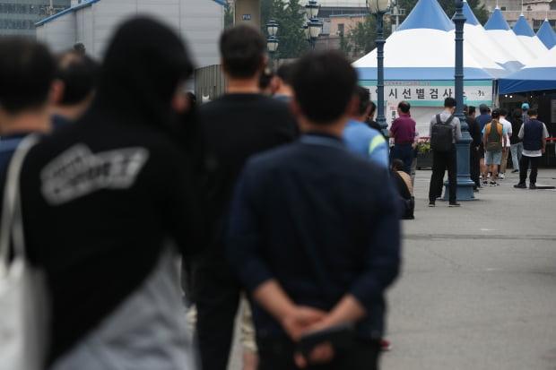 ソウル駅近くにあるCOVID-19臨時選別診療所前で並んでいる人々。医療スタッフが新型コロナウイルスの検査を行っている場面 (ニュース1提供・韓国経済著作権)