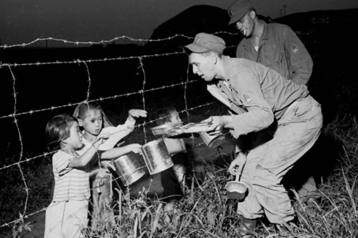 ทหารสหรัฐกำลังมอบอาหารกระป๋องให้เด็กเกาหลีในช่วงสงครามภาพขาวดำ