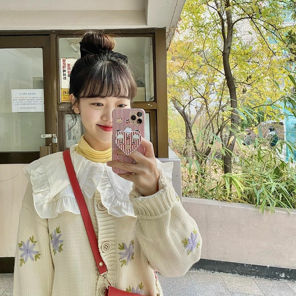 fille avec des franges et un chignon haut selfie dans le miroir avec une coque de téléphone de Earpearp