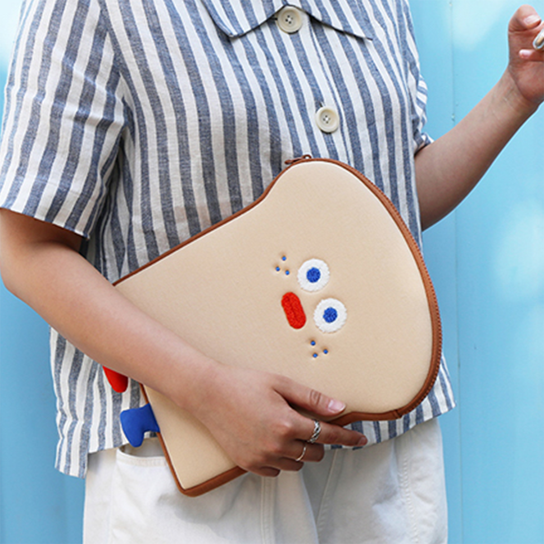girl holding up Romane toast laptop pouch with arm