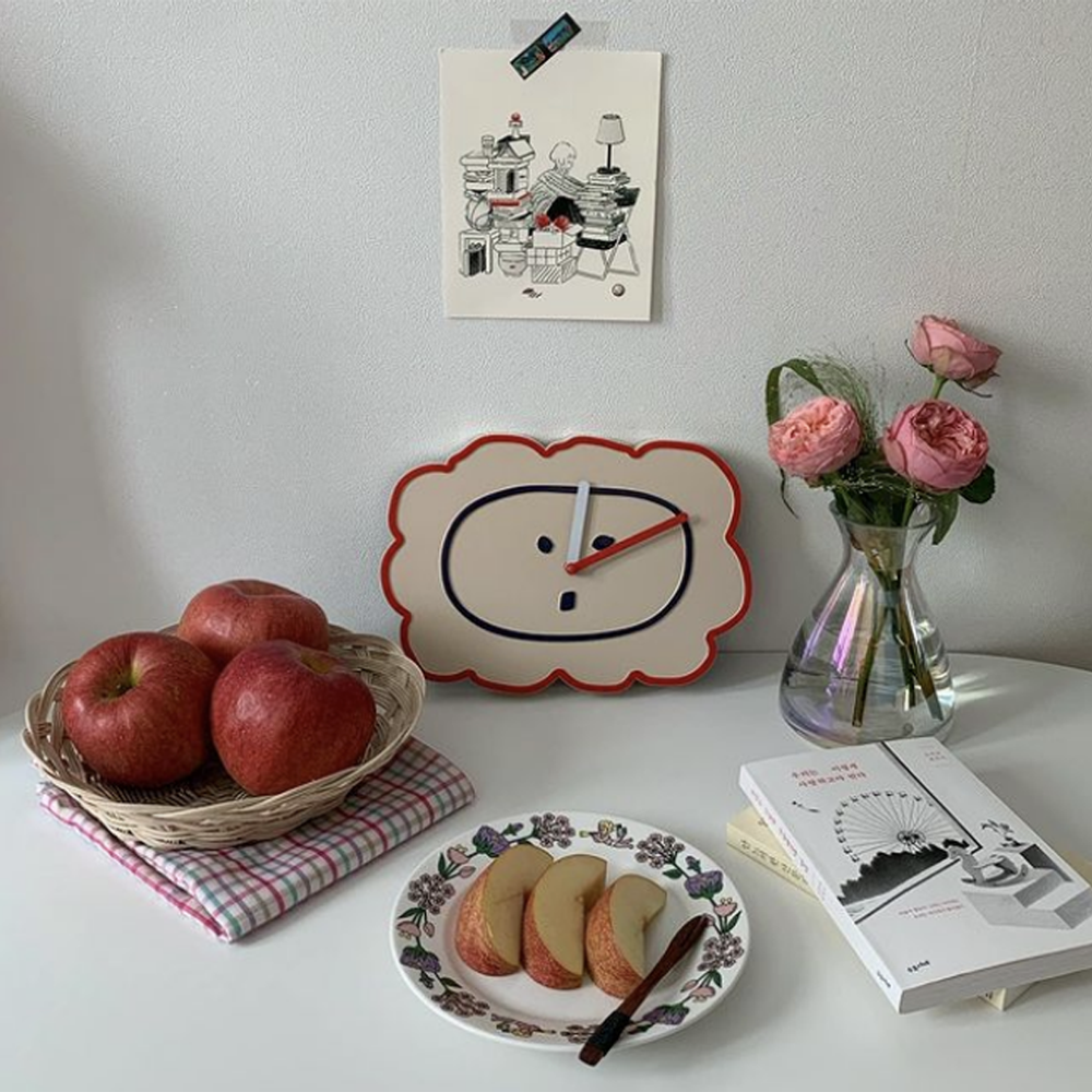 pommes sur une assiette, livres et horloge Romane sur une table blanche