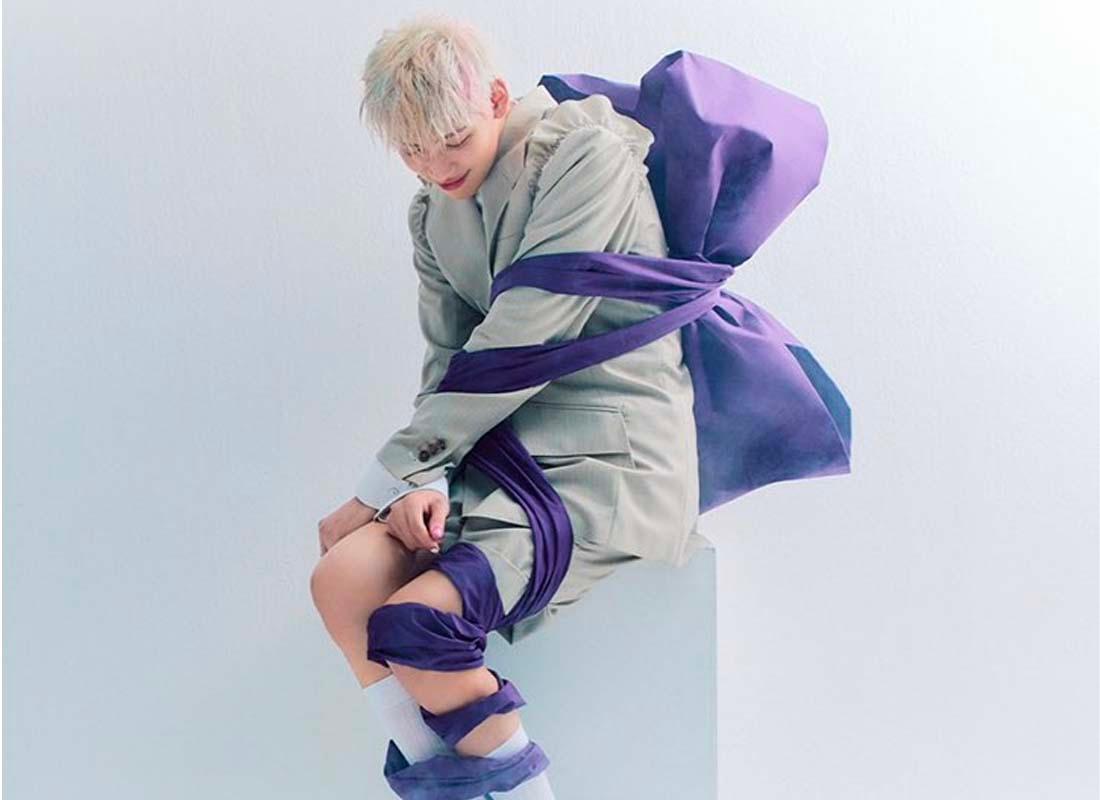 ศิลปินแบมแบม GOT7 นั่งบนแท่นสีขาวในภาพโปรโมทอัลบั้ม 'riBBon' พร้อมริบบิ้นสีม่วงพันรอบตัว