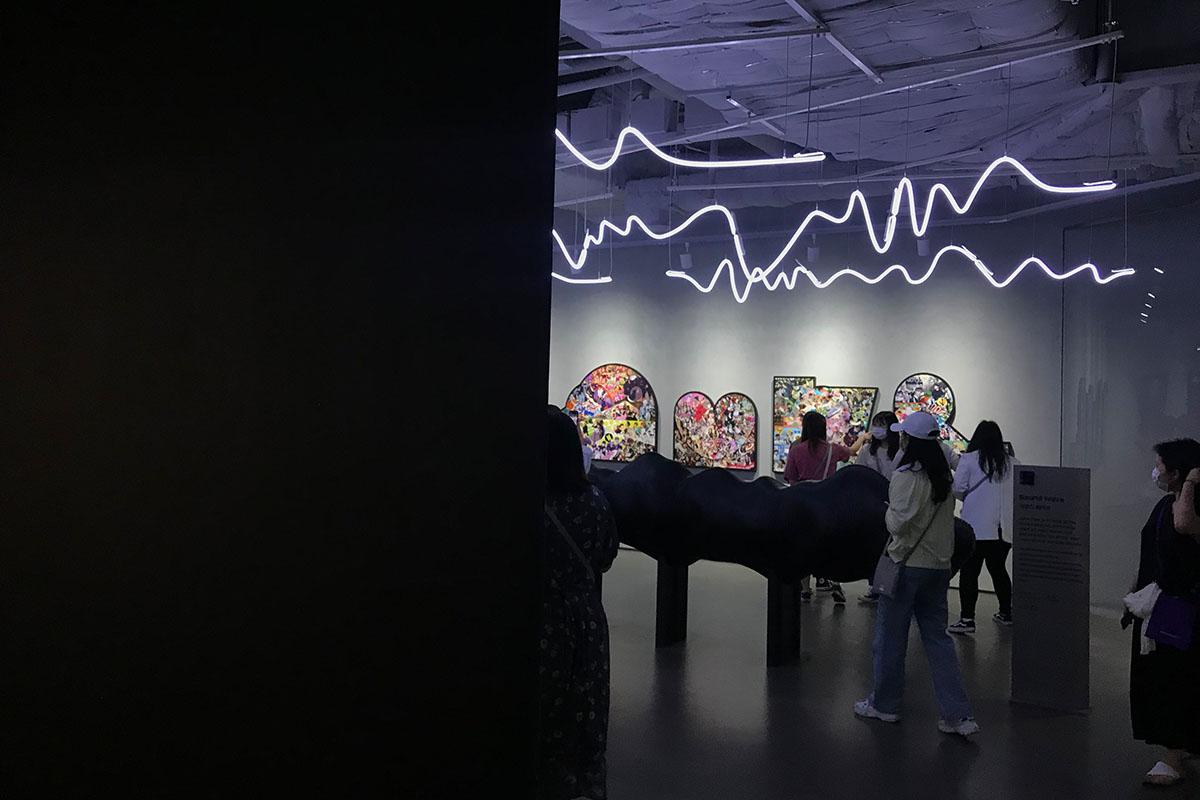 Visitors looking at exhibition that features different collages