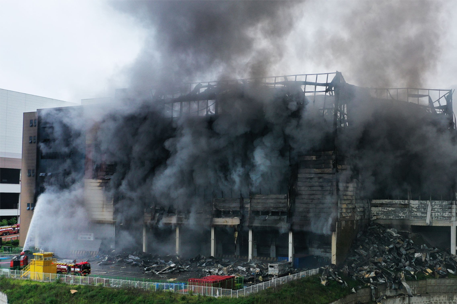 倉庫的外部被火焰和煙霧包圍，結構已經受到嚴重損壞。