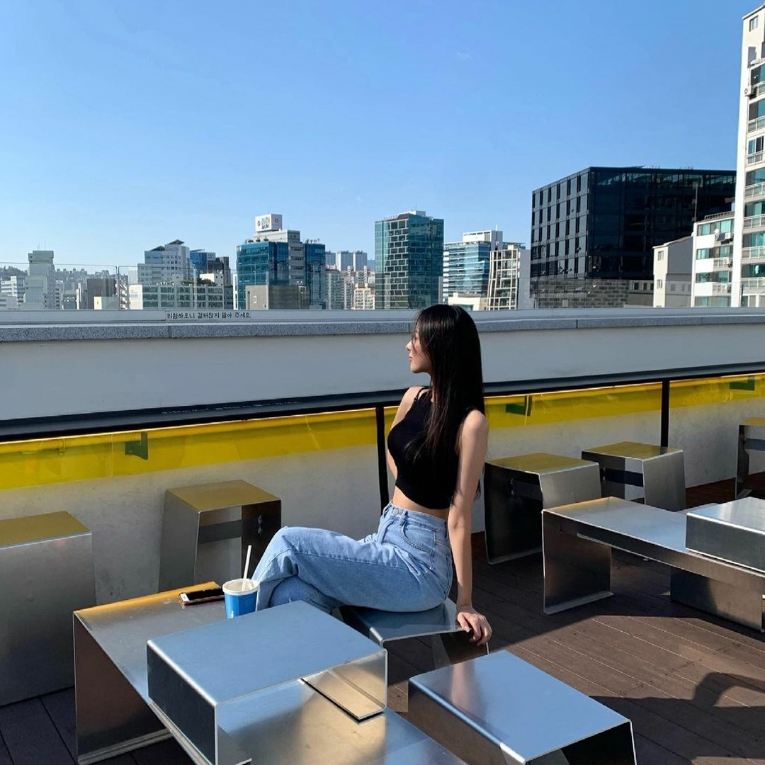 girl in black tank top sitting at Cafe Yeonmujang rooftop enjoying the view