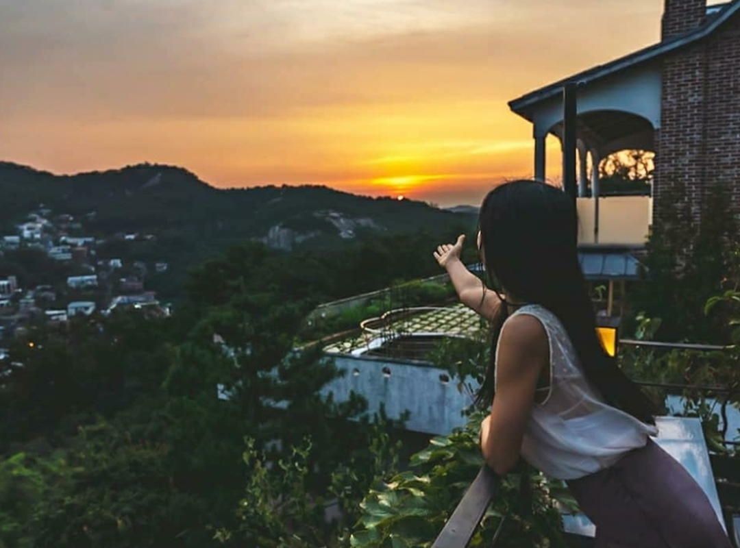 girl looking out at the view of Sanmotunggi Coffee rooftop during sunset