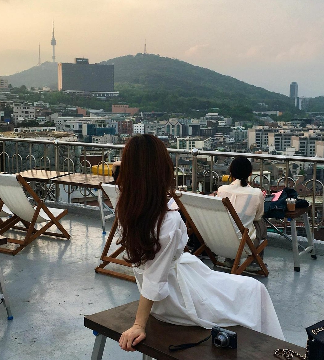 girl in white dress sitting on a bench at Mmm Records rooftop
