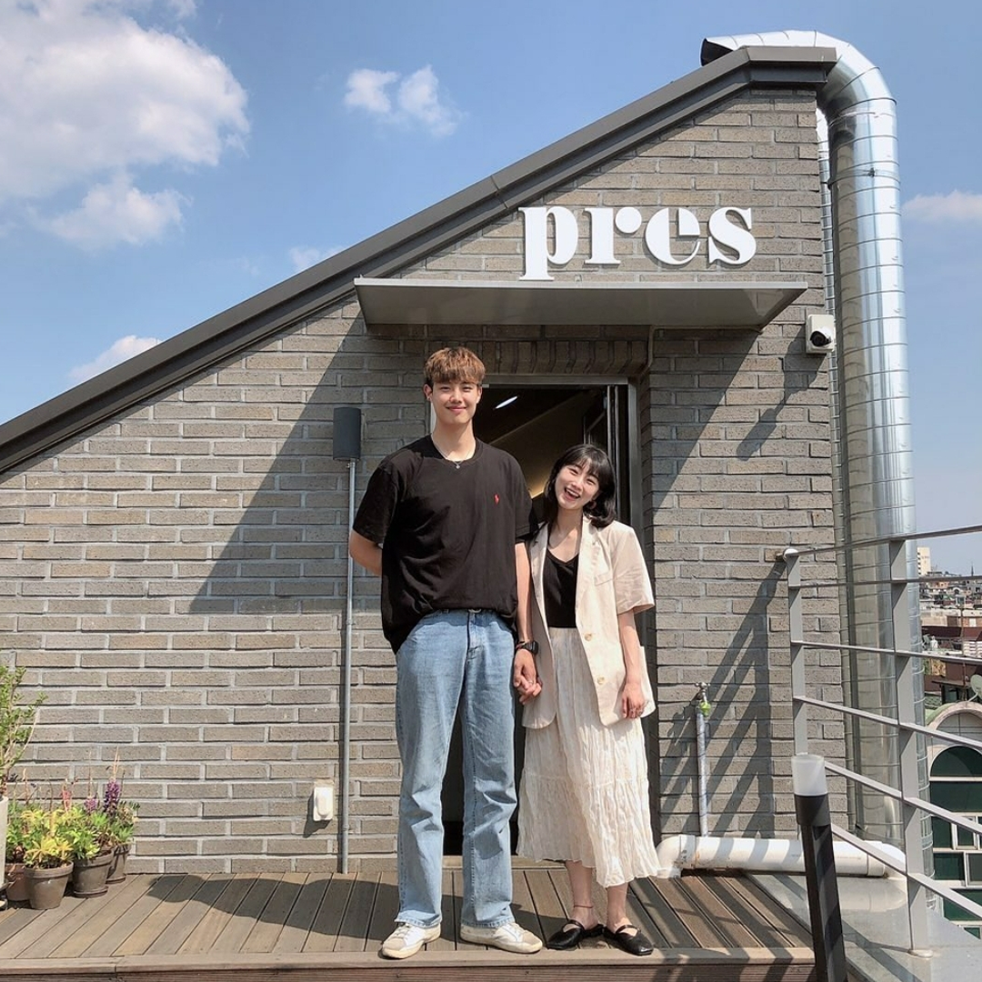 Korean couple holding hands standing infront of Pres Coffee rooftop