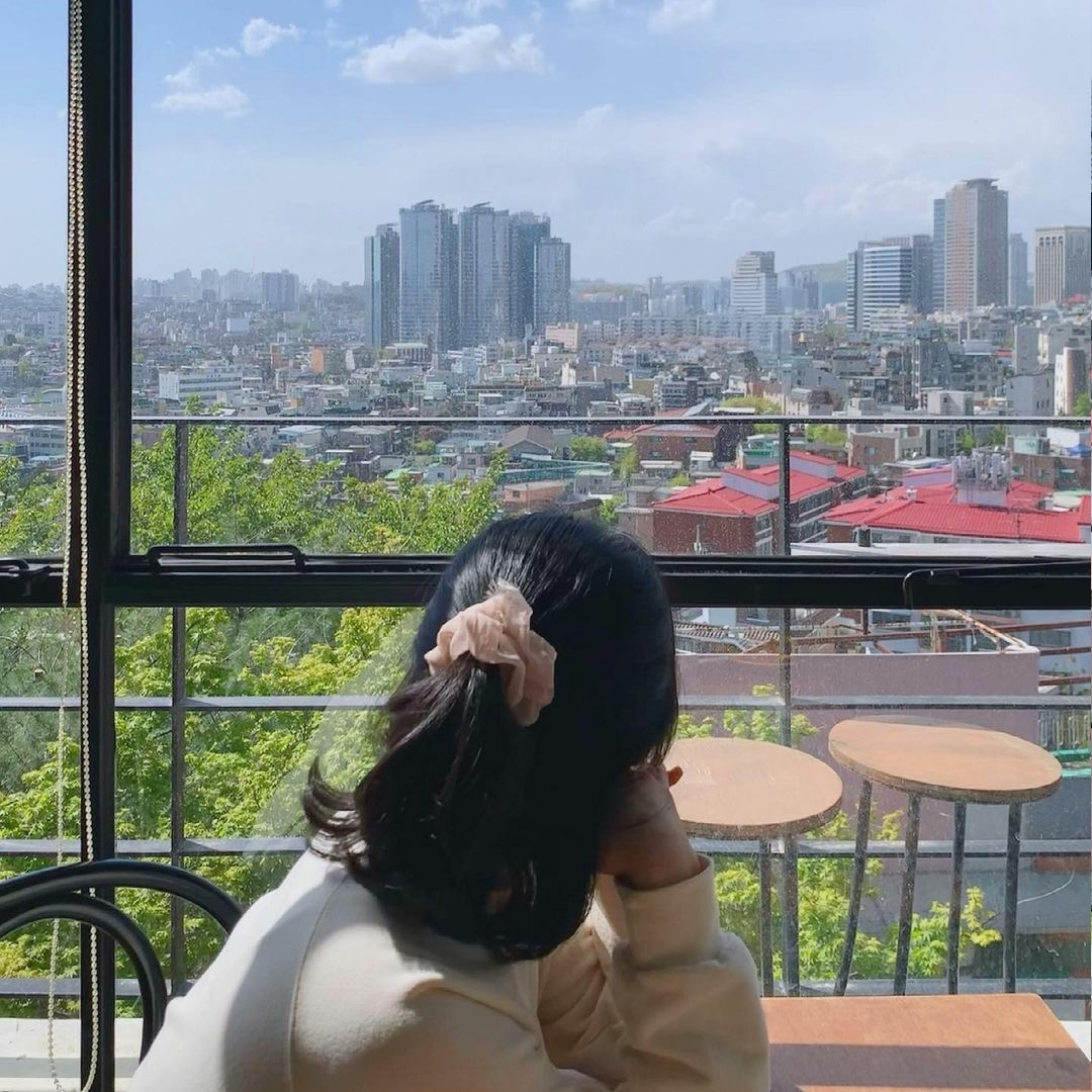 girl looking out at the view of Haebangchon sitting at Cafe Moonee rooftop