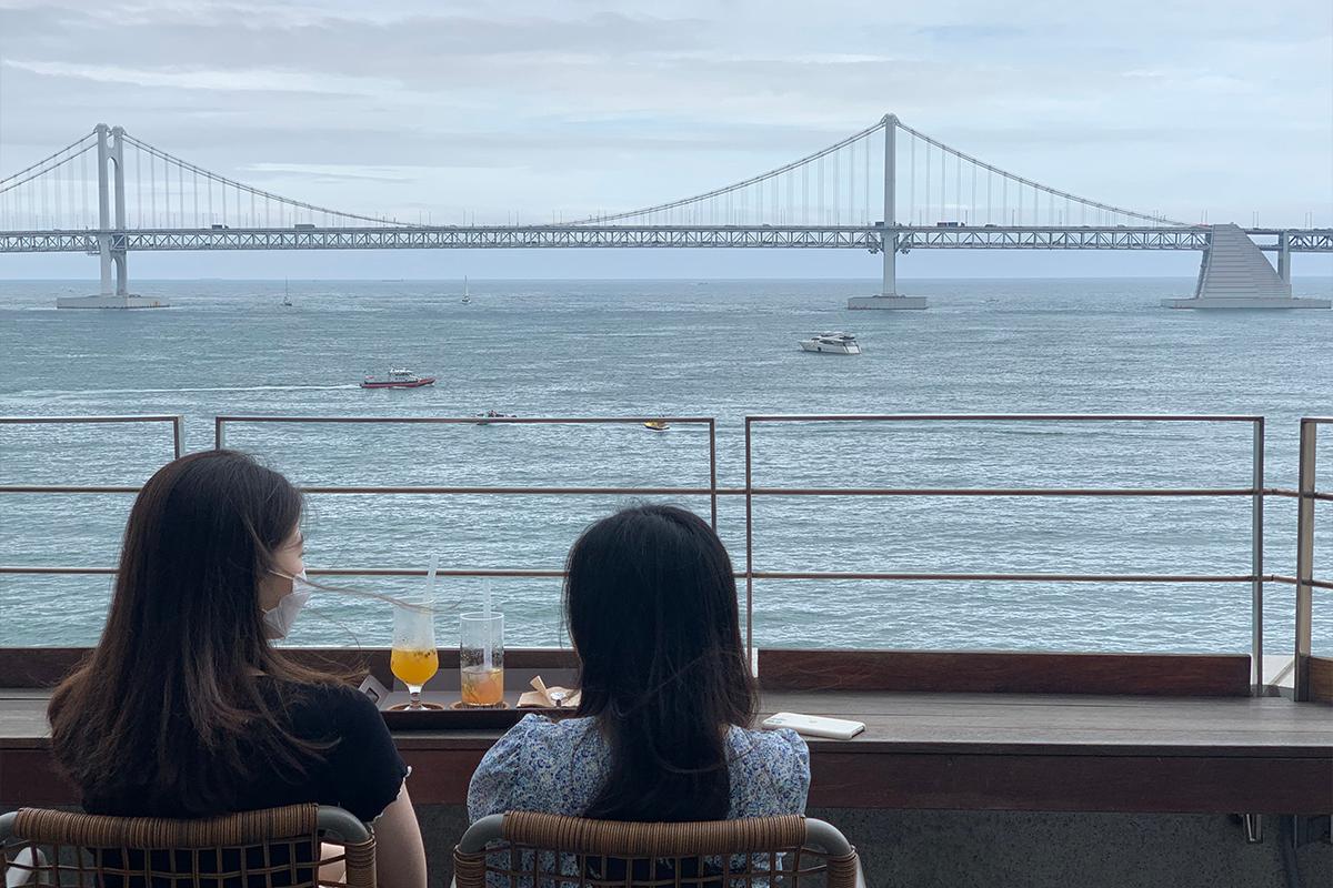釜山CUP&CUP咖啡廳的屋頂露天座位區，背靠廣安大橋的美麗海景