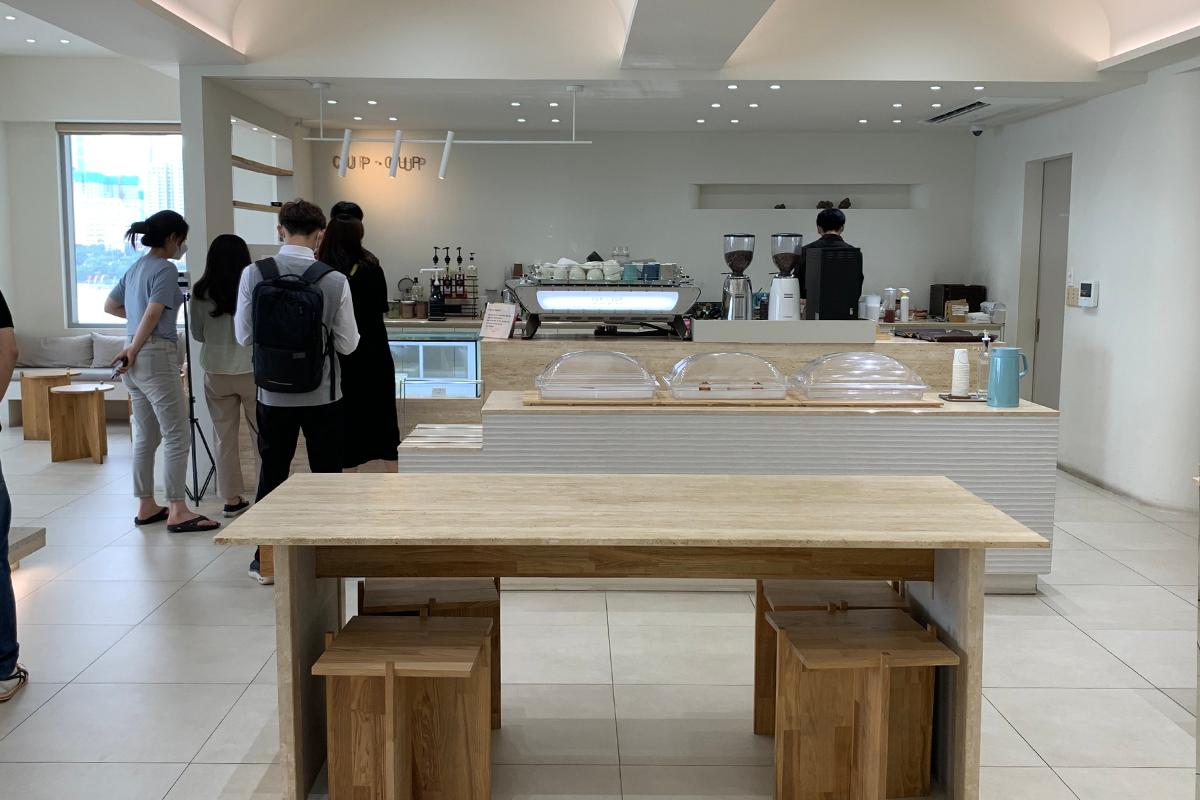 釜山CUP&CUP咖啡廳室內一角，明亮現代的設計，顧客正在點餐