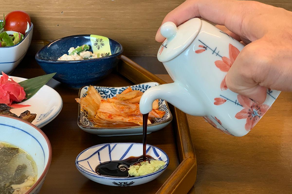 Customer pouring soy sauce into small bowl