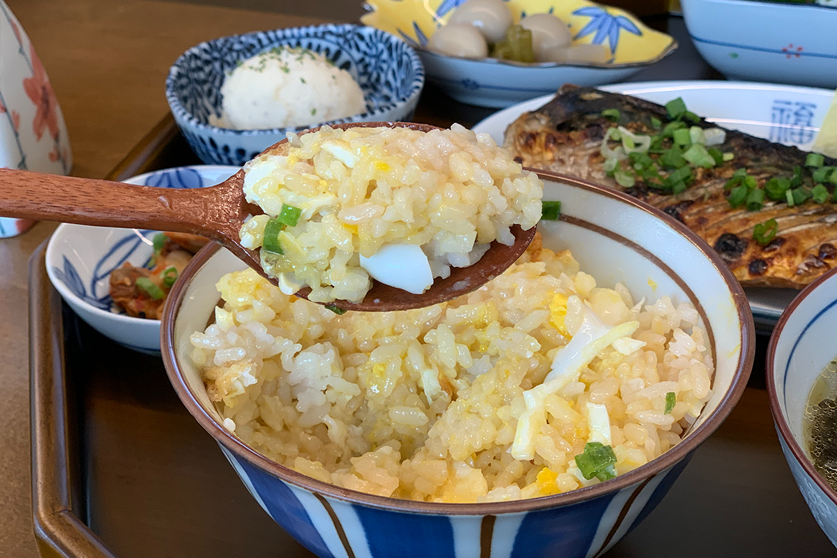 用木勺舀起的蛋飯，煎蛋上的蛋黃流出。