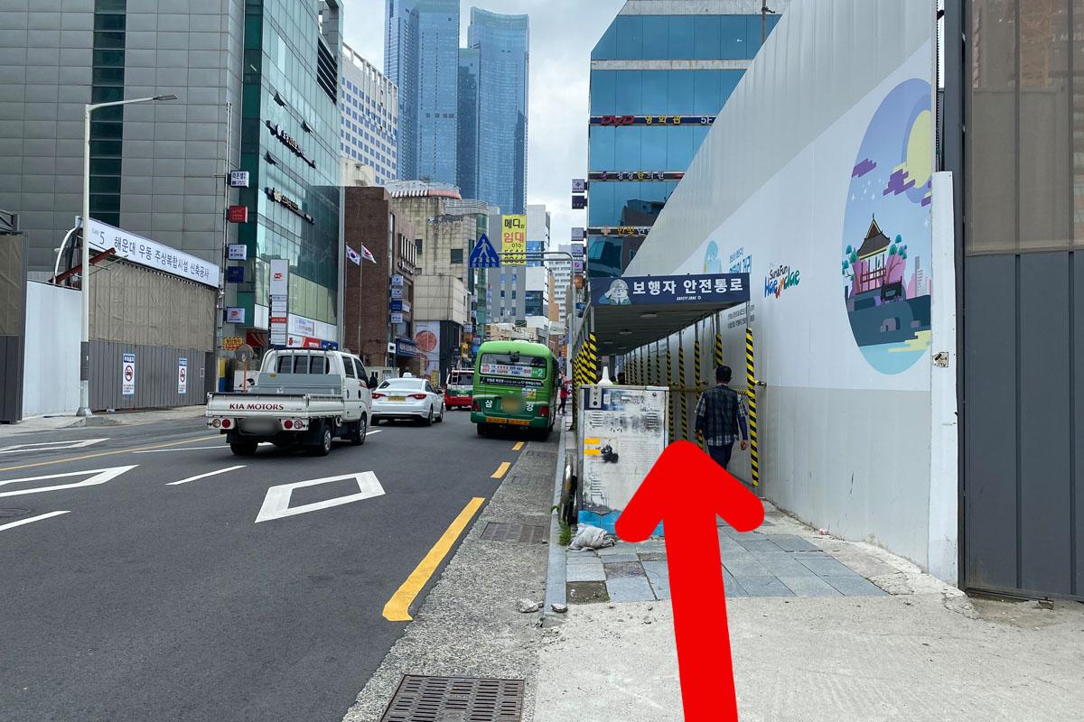 Continua por una calle tranquila en Busan rodeada de edificios comerciales.