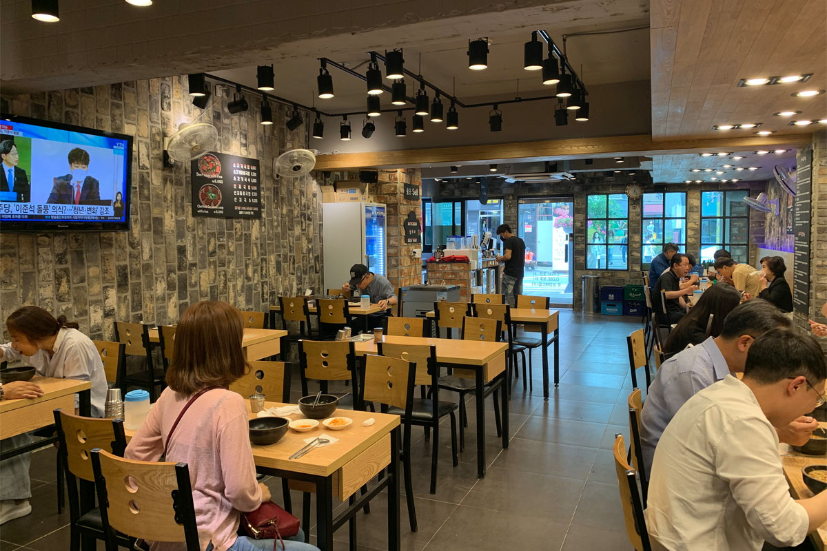 Không gian nhà hàng Haeundae Wonjo Halmae Gukbap với khách ngồi ăn và trang trí hiện đại ở Busan, Hàn Quốc.