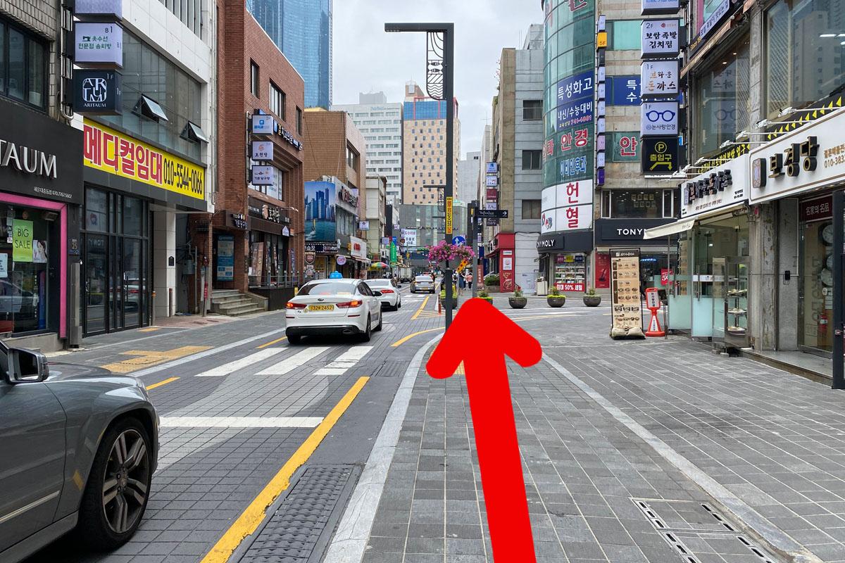 Una calle en Busan donde se alinean coches y locales de negocios.