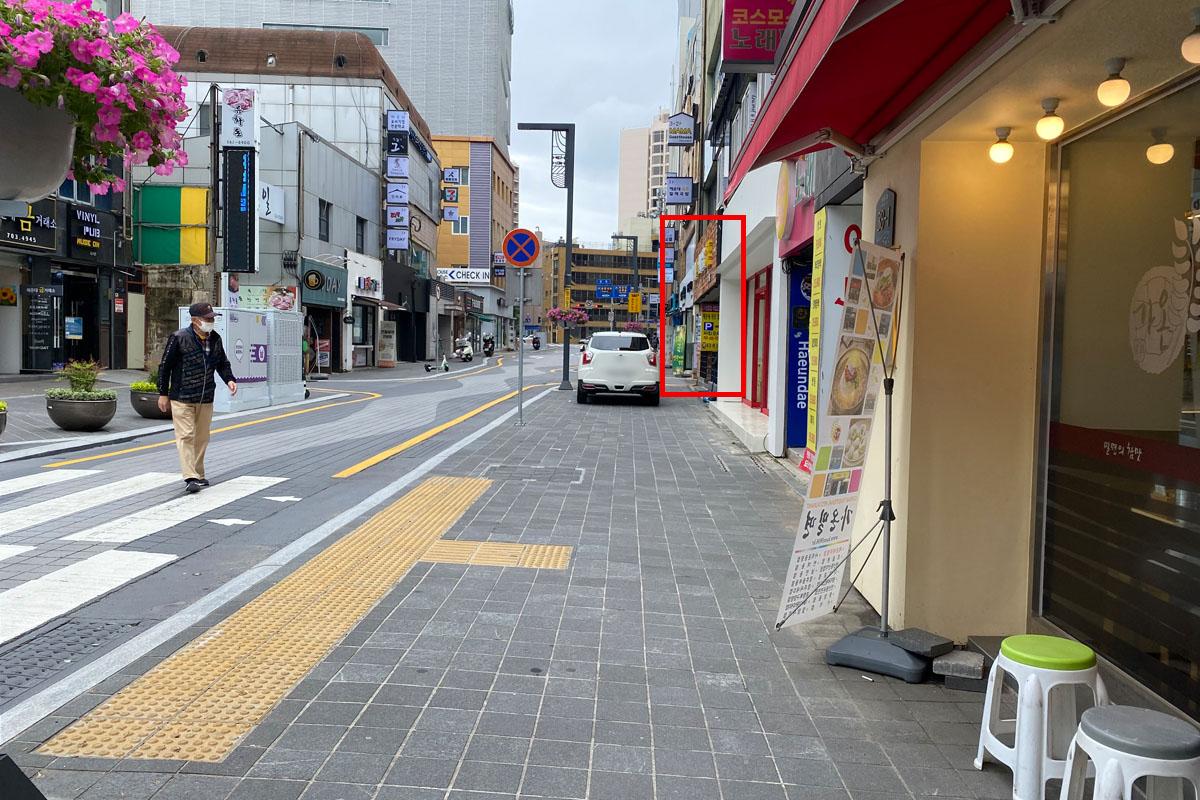 Calle bulliciosa en Busan con coches y tiendas.