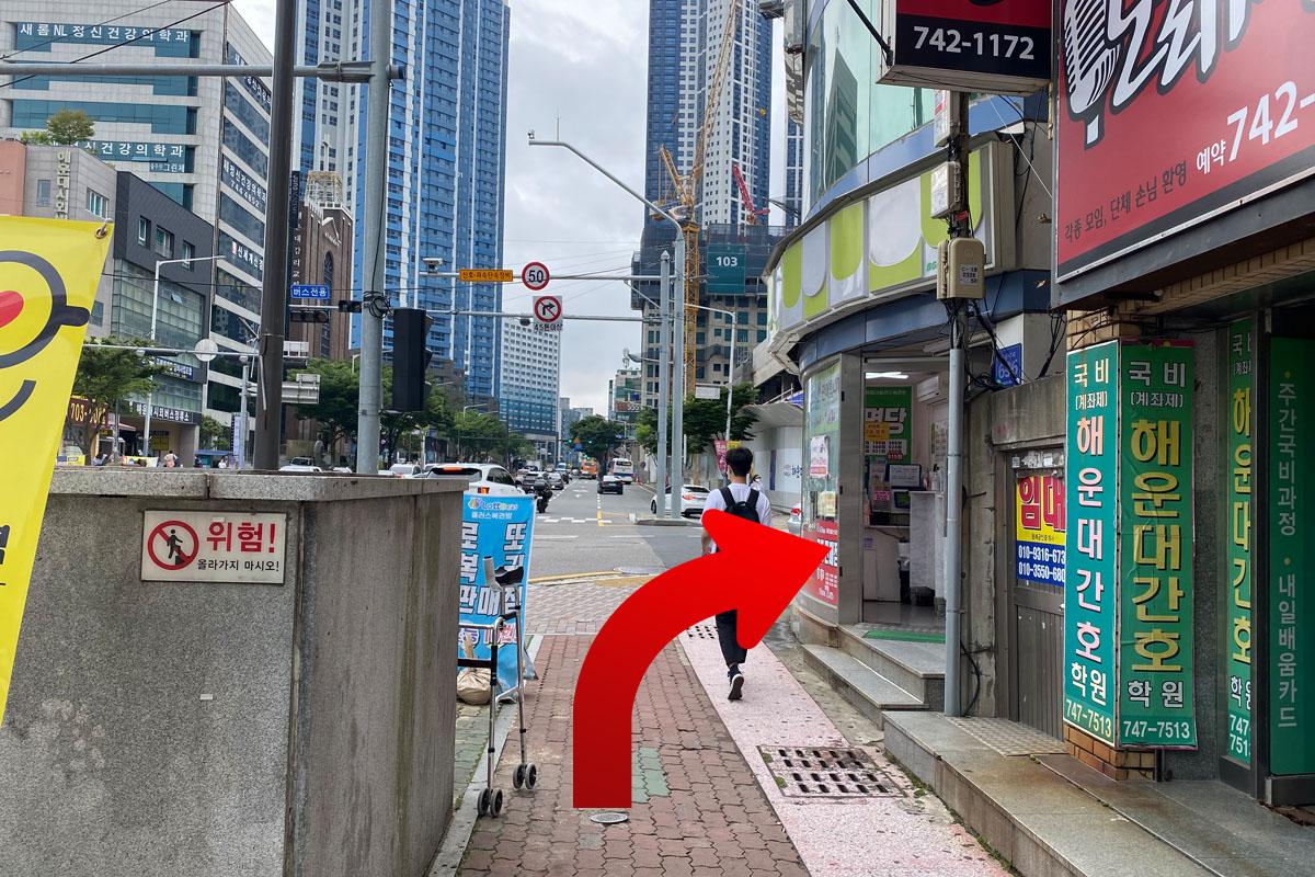 Calle de Busan con árboles y una tienda de conveniencia CU a la vista.