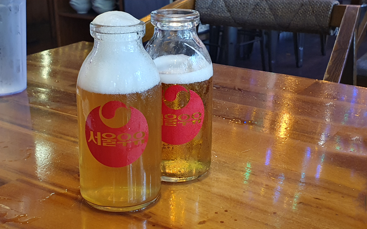Two orders of beer served in glass milk bottles