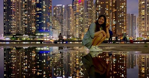 a girl posing at bay 101 in busan with night lights and skyscrapers