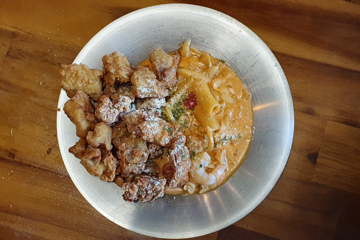 Close-up shot of fried chicken dish with pasta in rose sauce