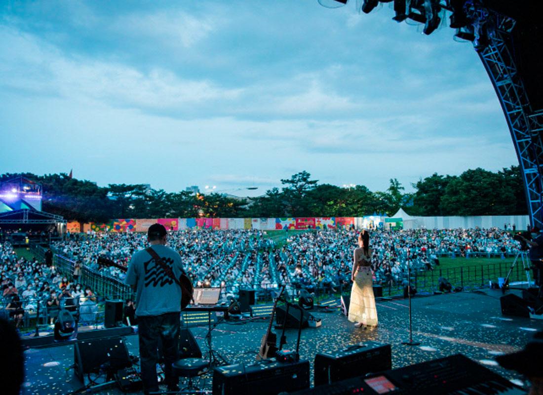 วงดนตรีแสดงคอนเสิร์ตบนเวทีกลางแจ้งในงาน Beautiful Mint Life 2021 ที่กรุงโซล ประเทศเกาหลีใต้ โดยมีผู้เข้าชมนั่งชมอยู่บนสนามหญ้าในสวนโอลิมปิก