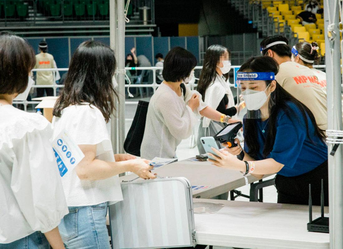 ผู้ชมงานคอนเสิร์ตกำลังยื่นบัตรและโทรศัพท์เพื่อเช็คอินเข้างานที่บริเวณทางเข้า ณ สวนโอลิมปิก โซล, เกาหลีใต้